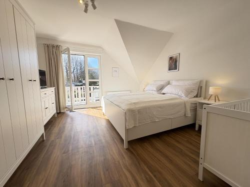 a white bedroom with a bed and a window at Allee 1G - Meerzeit in Dahme