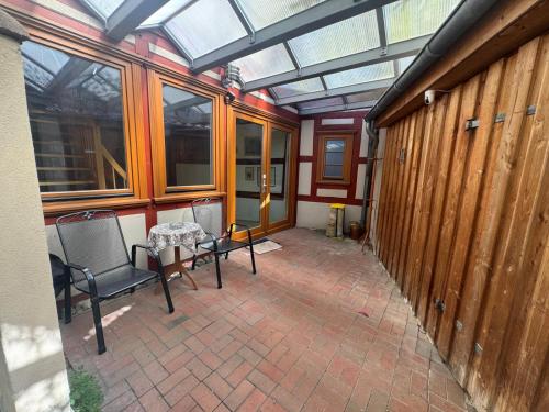 ein Wintergarten mit Tisch, Stühlen und Fenstern in der Unterkunft Hotel Katharinenhöfchen in Salzwedel