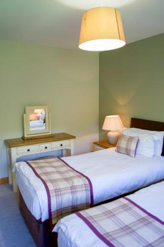 a bedroom with two beds and a table and a lamp at Apple Tree Lodge in Errol