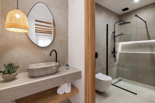 a bathroom with a sink and a toilet and a mirror at Onar -Quiet Luxury Suites with Private Jacuzzi-Ideal for Couples in Archangelos
