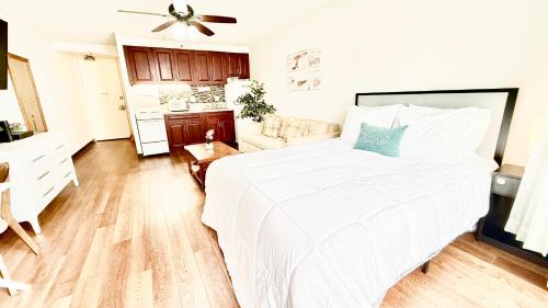 a bedroom with a large white bed and a kitchen at Free parking Comfy central Waikiki in Honolulu