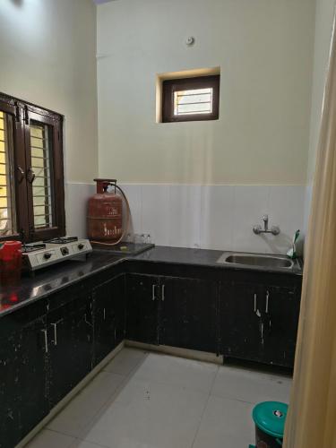 a kitchen with black cabinets and a sink and a window at RS Homestay in Bareilly