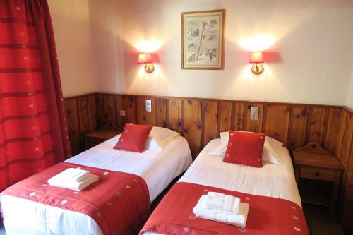 two beds in a room with red and white sheets at Le Dahu in Chamonix-Mont-Blanc