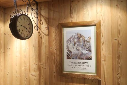 a clock on a wall with a picture of a mountain at Le Dahu in Chamonix-Mont-Blanc