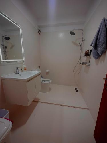 a white bathroom with a sink and a toilet at Coral Studio Apartment in Shëngjin