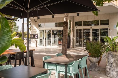 an outdoor cafe with tables and chairs and an umbrella at Hotel SB Express Tarragona in Tarragona