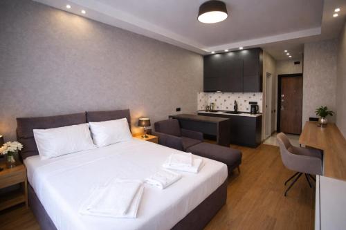 a bedroom with a large white bed and a kitchen at DreamSide Aparthotel in Batumi