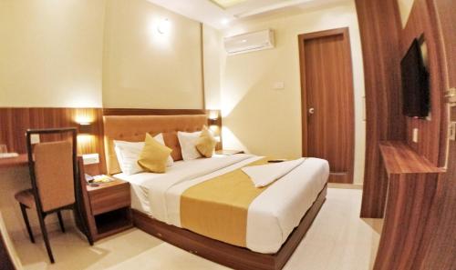 a hotel room with a bed and a table and a chair at Hotel Emerald Near T2 International Airport Mumbai in Mumbai