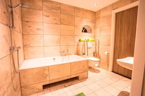 a bathroom with a tub and a toilet and a sink at De Sterre in Losser