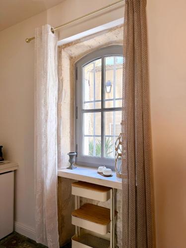 a window in a room with a table and a curtain at Le Voisin des Arènes in Arles