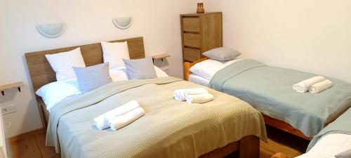 two beds in a room with towels on them at Báránykő Apartman in Pásztó