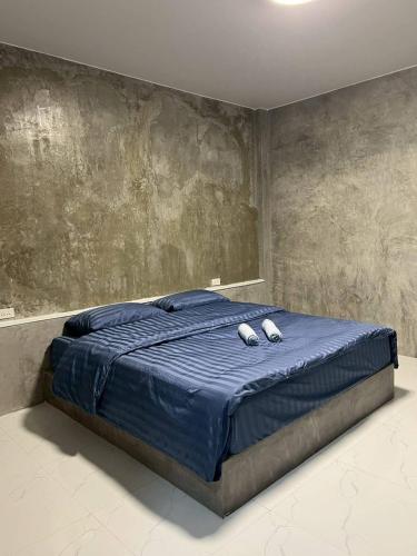 a bedroom with a blue bed with two slippers on it at K-Am คราม อมตะ รีสอร์ต in Ban Yan Su