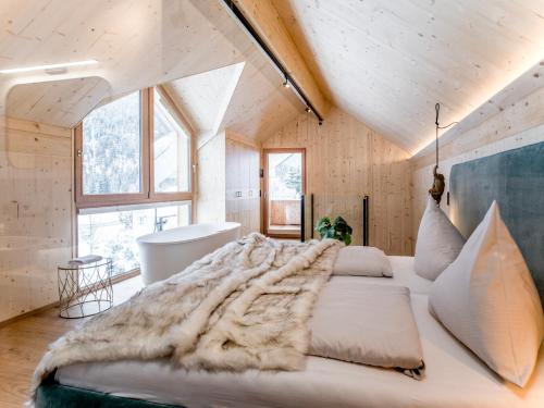 a bedroom with a large bed and a bath tub at Bio Chalets Alpegg in Waidring