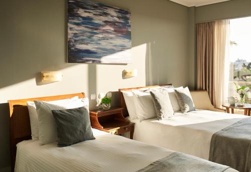 a hotel room with two beds and a painting on the wall at Golden Sun Hotel in Athens