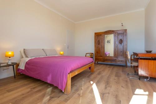 a bedroom with a large bed with a pink blanket at Moleloca - Casa Bacolla in Cocconato
