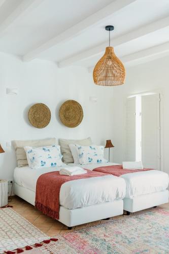 a white bedroom with two beds with red and blue pillows at Casa do Céu - Casas do Levante in Olhão