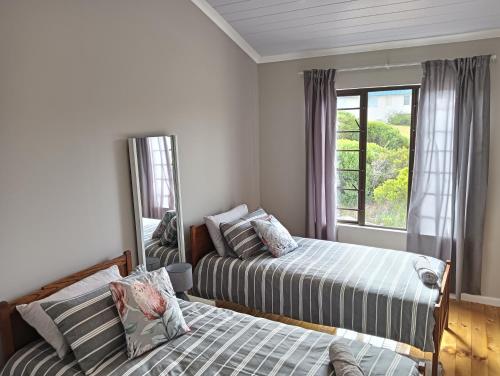 a bedroom with two beds and a window at Beach Walk by Salted Fynbos Staying in Pearly Beach