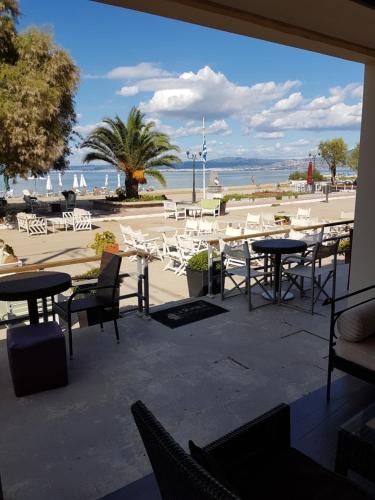 a patio with tables and chairs and a view of the beach at Hotel Pithari in Agia Triada