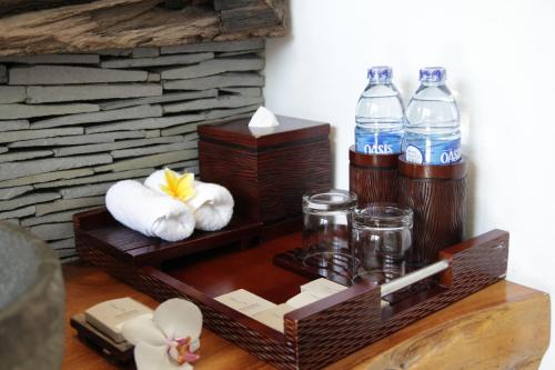 a wooden shelf with two bottles of water and towels at The Samara Villas & Restaurant in Ubud