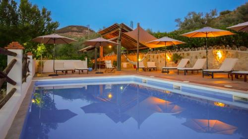 a swimming pool with umbrellas and tables and chairs at Casa Olea in Priego de Córdoba