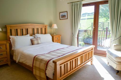 a bedroom with a large bed and a balcony at Plum Tree Lodge in Errol
