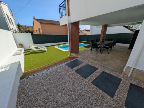a patio with a table and chairs and a yard at VILLA Pinemar & Relax in Pineda de Mar