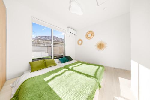 a bedroom with a bed with green sheets and a window at Liber 1 Tachikawa in Tachikawa