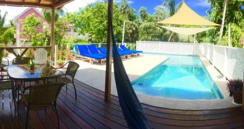 a deck with a swimming pool and a table and chairs at Hummingbirds Cabins in Caye Caulker