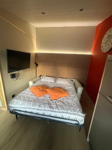 ein kleines Bett in einem Zimmer mit einer Uhr an der Wand in der Unterkunft Ostivigne in Ath