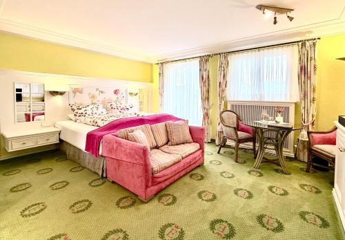 a bedroom with a pink bed and a chair and a table at Boutique Hotel Villa am See in Hagnau