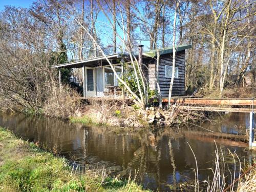 a house on the side of a river at Het Groene uitzicht in Bantega