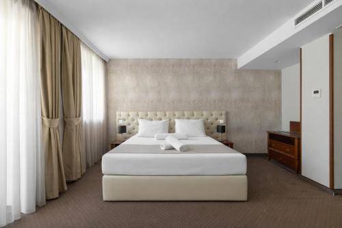 a bedroom with a large white bed and curtains at Alexandar Square Boutique Hotel in Skopje