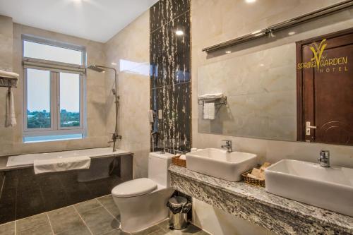 a bathroom with two sinks and a toilet and a window at Spring Garden Hotel in Long Khanh