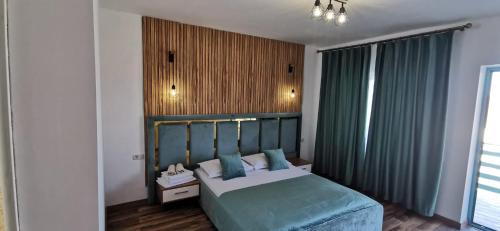 a bedroom with a bed with a green headboard at Pensiunea Aura Deltei in Murighiol