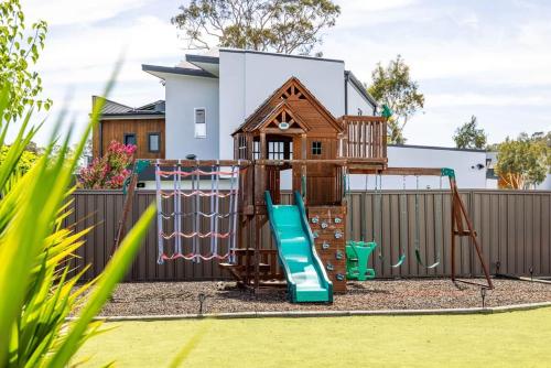 a playground in front of a fence with a slide at Charming 5-Bedroom House in Harrison