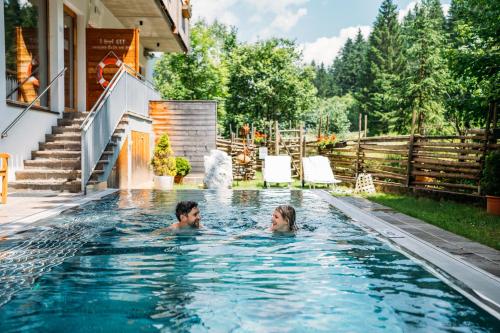 a man and woman swimming in a swimming pool at Hotel Trattlerhof in Bad Kleinkirchheim