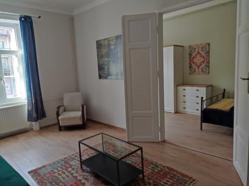 a living room with a bed and a glass table at Sunny side apartman in Sopron