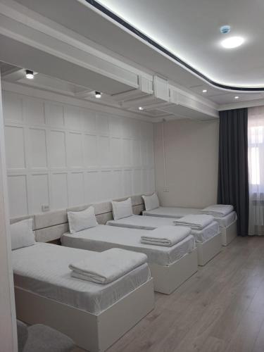 a room with four beds in it with a window at Safo Hotel Turkestan in Türkistan