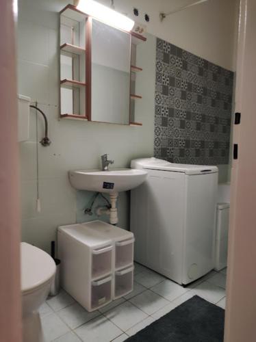 a white bathroom with a sink and a toilet at Sunny side apartman in Sopron