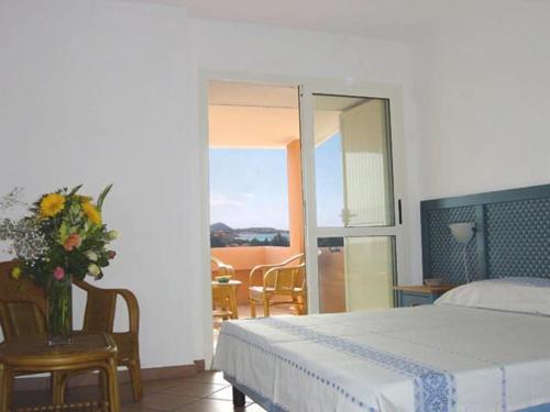a bedroom with a bed and a table with a vase of flowers at Residence la Chimera in Villasimius