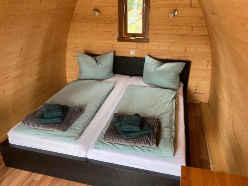 a bed in a cabin with two pillows on it at Nr 6 Camping Pod mit Terrasse und Seeblick in Langenbernsdorf
