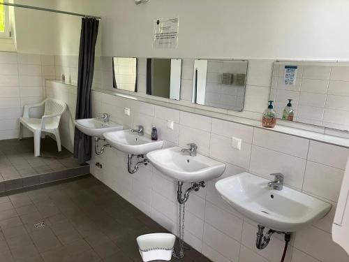 a bathroom with three sinks and two mirrors at Nr 6 Camping Pod mit Terrasse und Seeblick in Langenbernsdorf