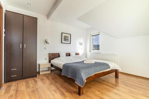 a white bedroom with a bed and a cabinet at Hestia Apartments in Berovo