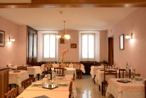 a restaurant with white tables and chairs and windows at Hôtel La Montagne Fleurie in Barèges