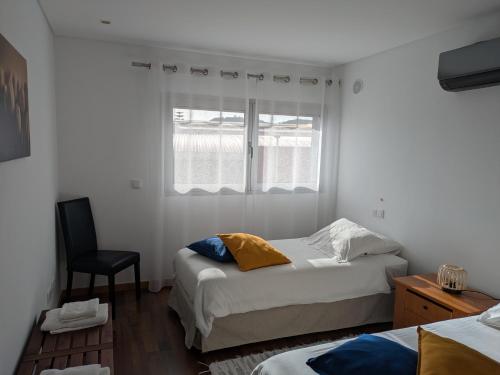 a bedroom with two beds and a chair and a window at Quarportugal in São Martinho do Porto