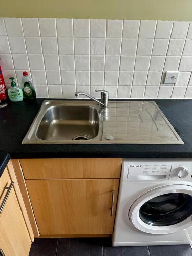 a kitchen with a sink and a washing machine at Superb Peaceful 1 bed apartment in St George. in Bristol