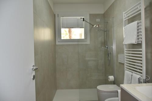 a bathroom with a shower and a toilet and a window at VELORA STAYS Florinas in Lido di Jesolo