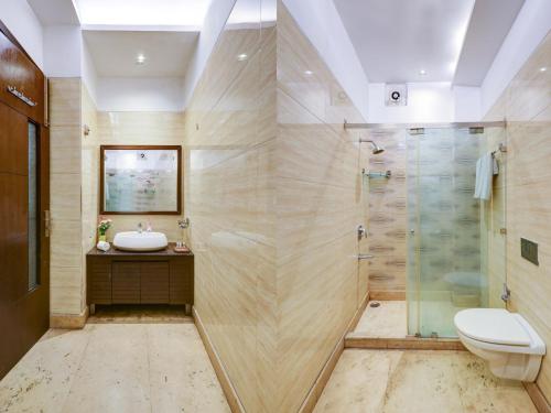 a bathroom with a shower and a sink and a toilet at Hotel The Metropolis Tourist Near Connaught Place And Ramakrishna Ashram Marg Metro Station in New Delhi