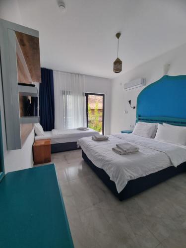 a bedroom with two beds and a blue headboard at Sunset Boutique Hotel & Apartments in Cıralı
