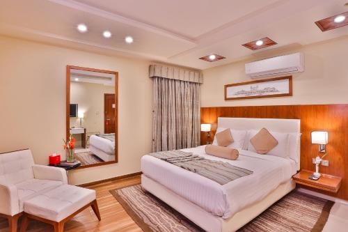 a bedroom with a large white bed and a mirror at Avari Xpress Faisalabad in Faisalabad